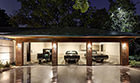 Large, 3-car garage with checkered tile floors, glazed concrete, and hardwood exterior, filled with 3 antique cars.