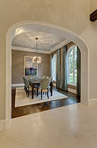Modern spacious dining room with arched entry, chandalier, large, arched windows, and hardwood floors