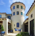 Exterior of modern house with a tall, round 3-story turret, with multiple windows, and built-in poured bench